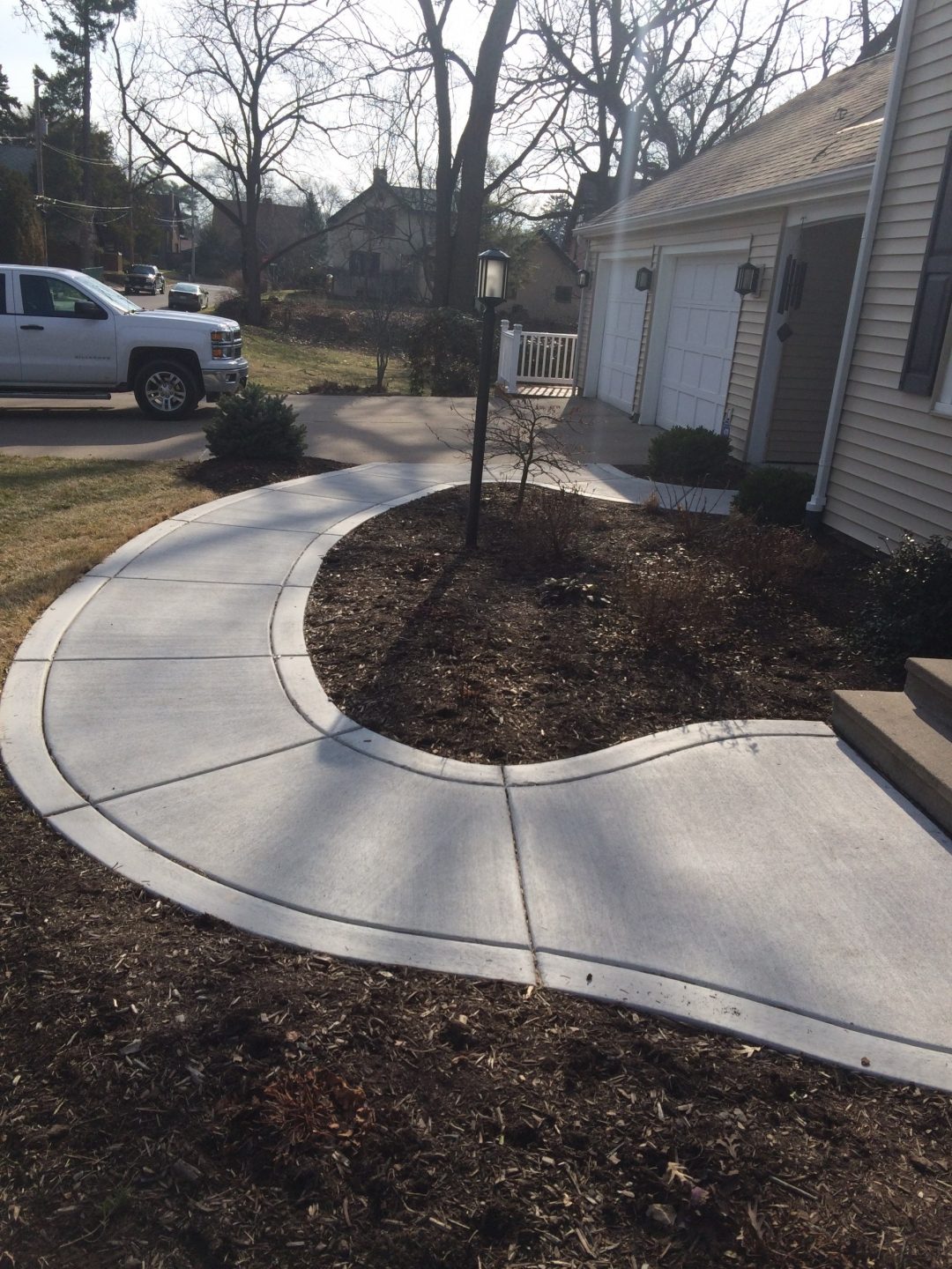 Curved concrete front walkway with broomed border leading to a home entry